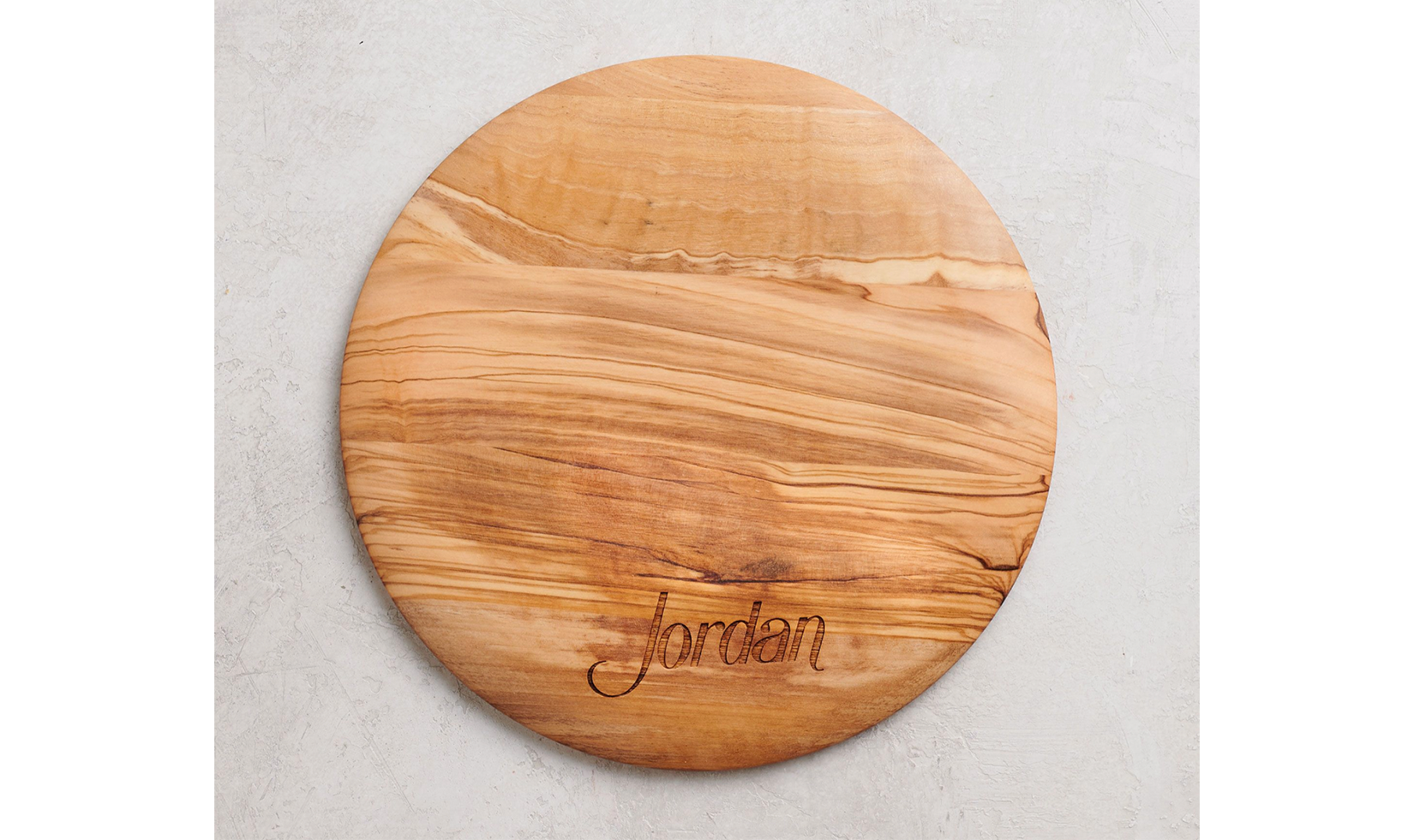 Round wooden cutting board with "Jordan" engraving.
