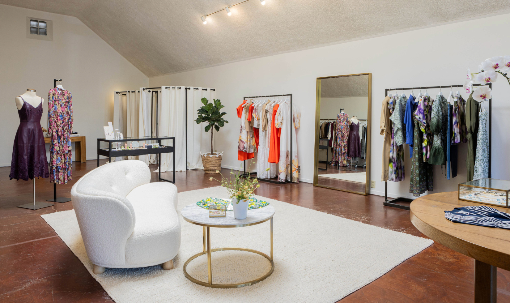 the interior of a clothing boutique with garments on display racks and a seating area