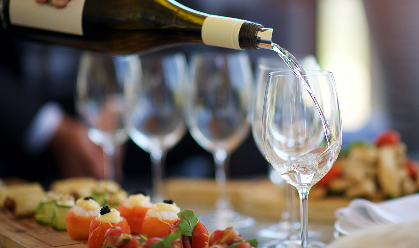 person pouring dessert wine into wine glasses on table with food pairings