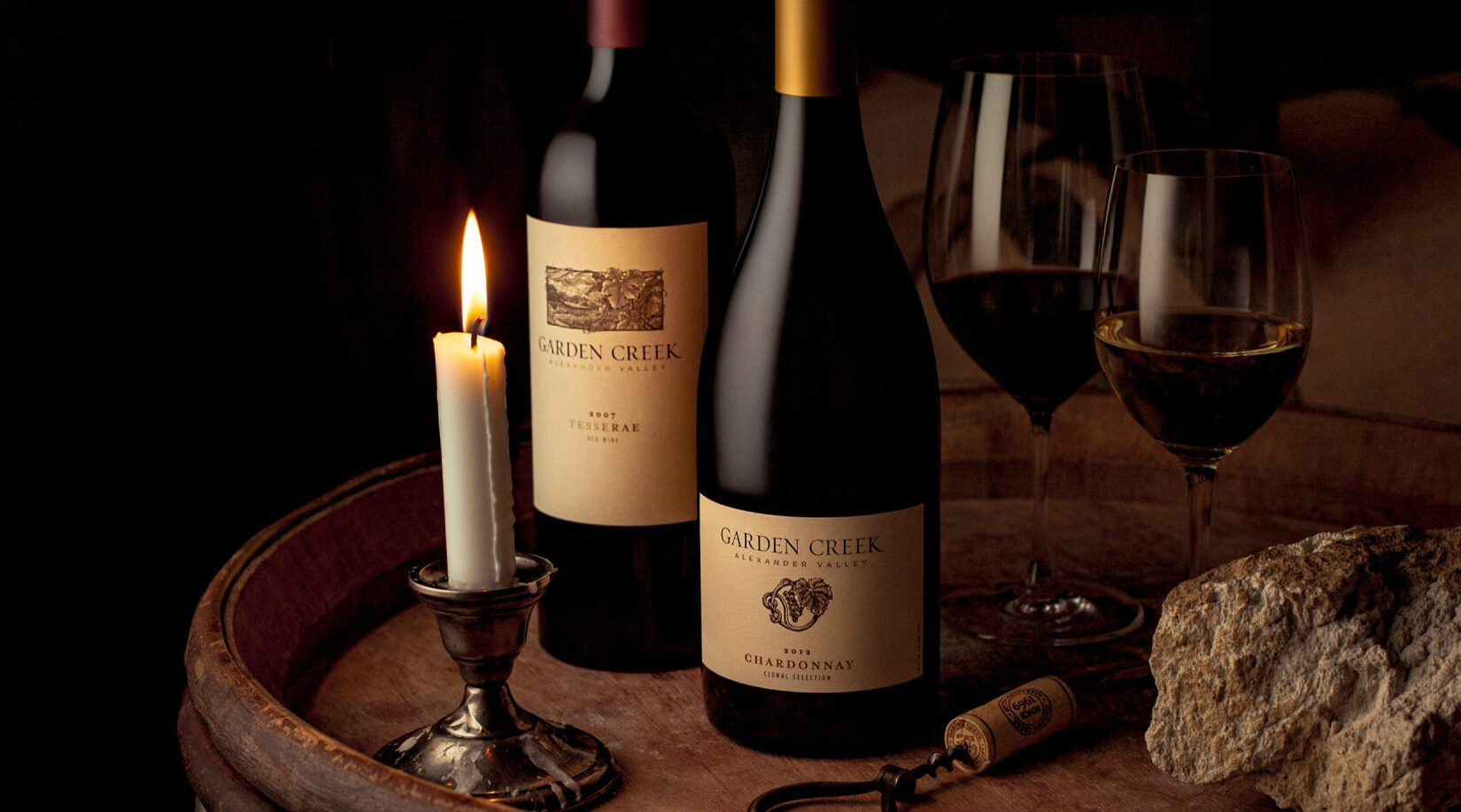 two wines on dimly lit barrel in cellar 